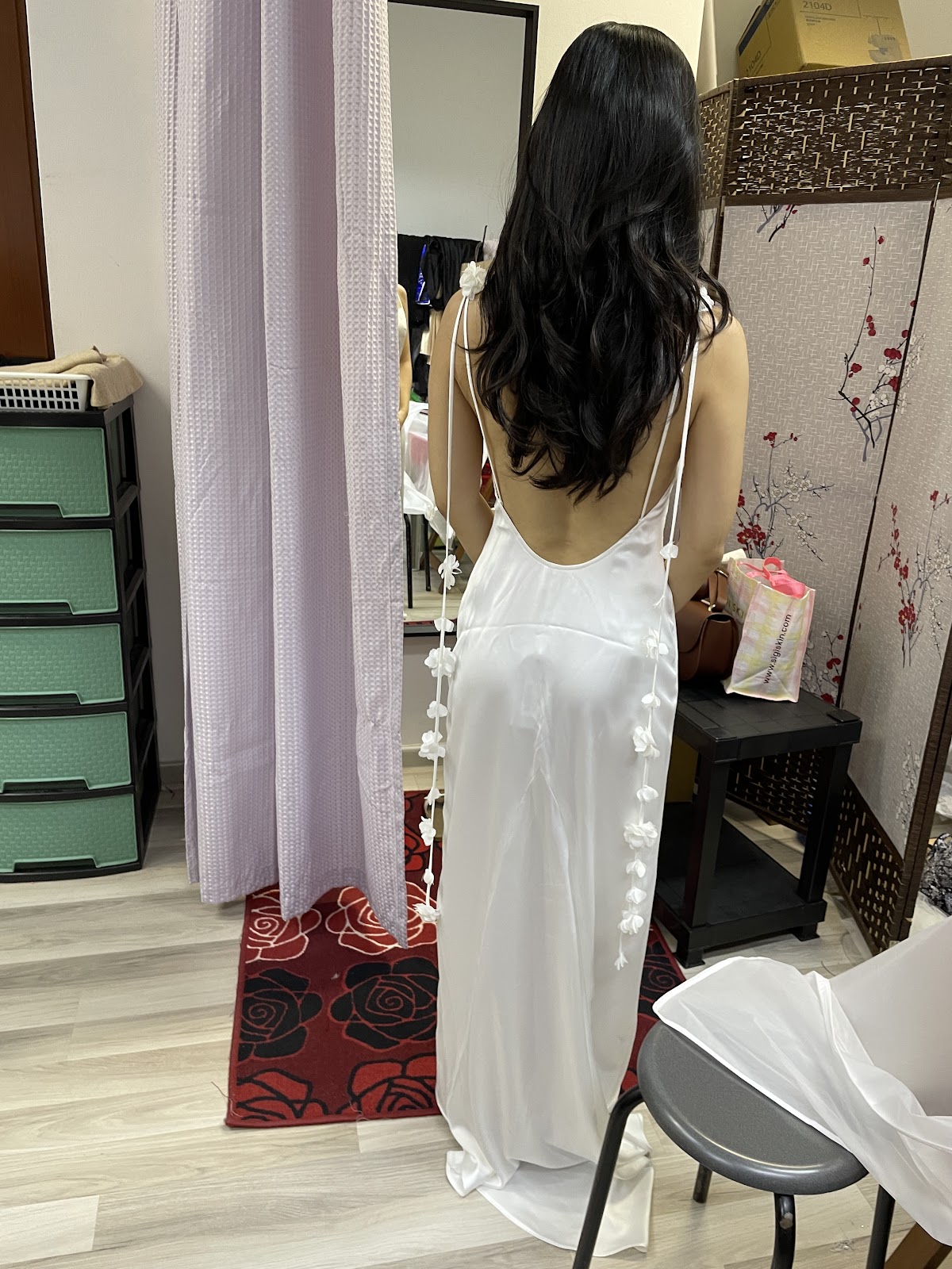 A customer being fitted in a white satin slip dress in the shop's fitting area